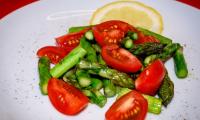 Picture of "Lukewarm green asparagus salad with cherry tomatoes" on a white plate.